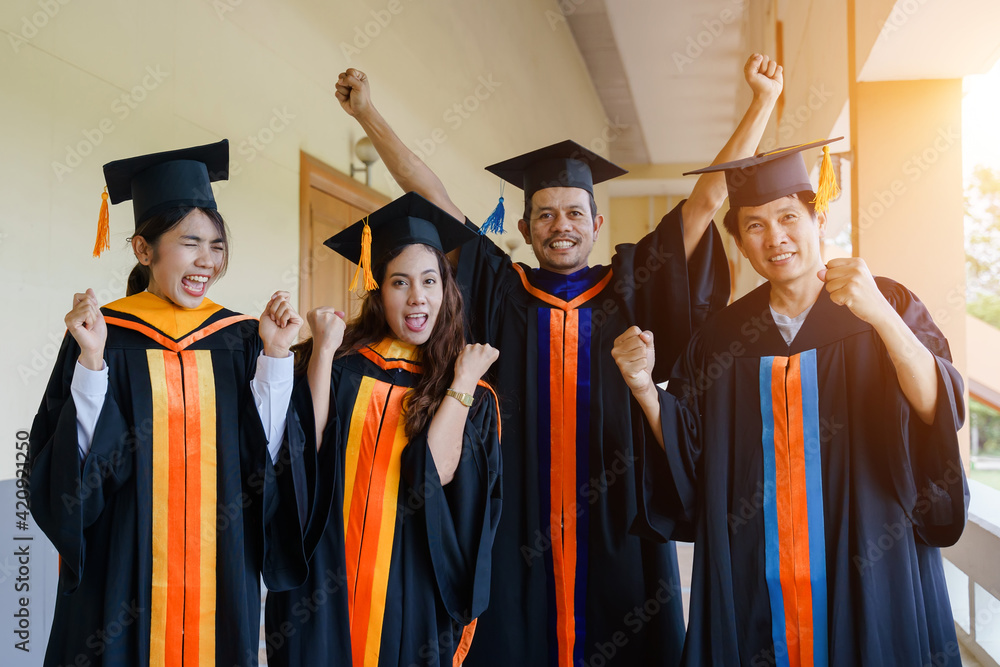 Wall mural The Asian university graduates in graduation gown and a mortarboard cap with a degree certificate in hand celebrating education achievement in the commencement ceremony. Congratulations to graduations