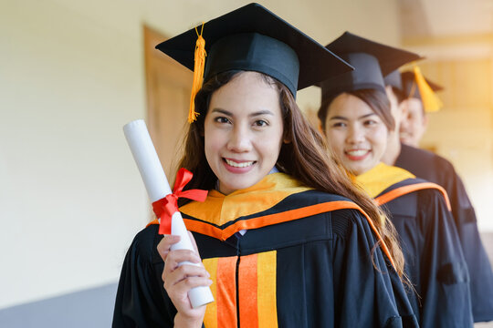 The Asian university graduates in graduation gown and a mortarboard cap with a degree certificate in hand celebrating education achievement in the commencement ceremony. Congratulations to graduations