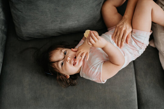 Toddler holding cracker relaxing on couch