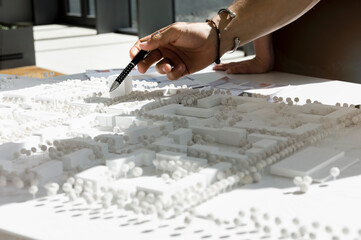 Close up of young architect pointing at architectural model.