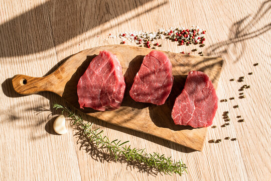 Thick slices of raw meat, rosemary, peppercorn - Powered by Adobe