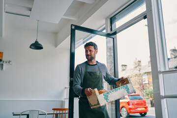 Man carrying crate of food supply into restaurant