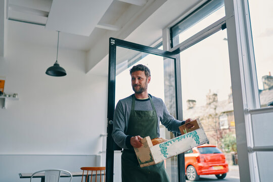 Man carrying crate of food supply into restaurant