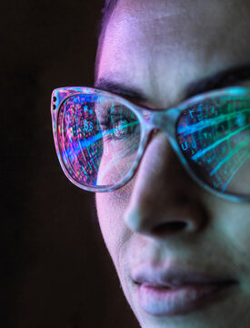 Electronic circuit board on computer monitor reflecting in glasses of a female engineer.