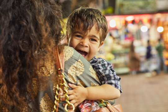 Mother carrying excited little boy in bazaar