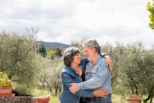 Portrait of senior couple, olive trees in background, Florence, Italy