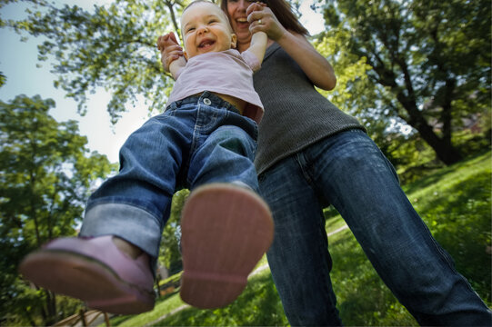 Low angle view of mother and baby girl playing on a lawn in a park.