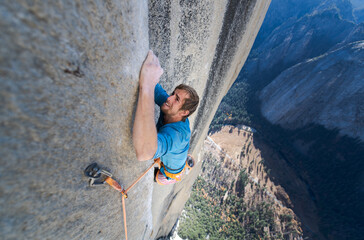 High angle view of mountaineer climbing up sheer wall of The Nose, El Capitan, Yosemite National Park. 