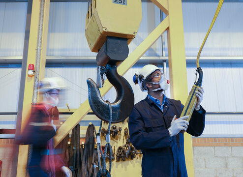 Engineer operating crane in turbine repair factory.