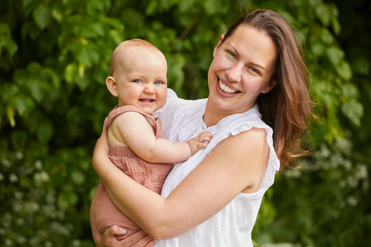 Portrait of mother and baby daughter smiling at camera.