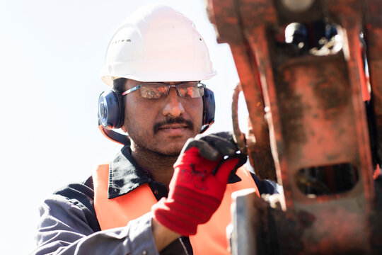 Male Engineer Wearing Hardhat And Ear Protectors Working On Construction Site.