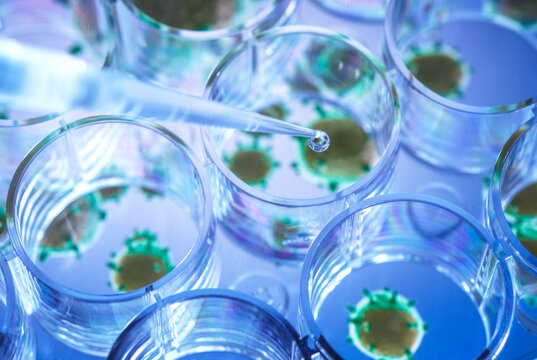 Scientist pipetting a experimental vaccine into a multi well plate with the virus in the background.