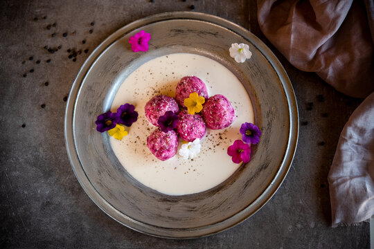 High angle close up of dumplings with baby pink turnips and blue cheese on white plate with grey rim.