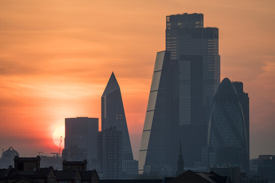 Sunset over the City of London, silhouettes of modern architectural landmarks. 