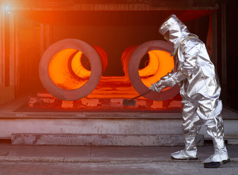 Man wearing silver heat-protective suit working in a steel factory.