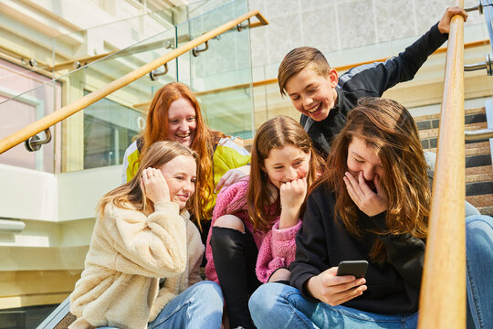 Group of teenage girls in a shopping mall, checking their mobile phones.