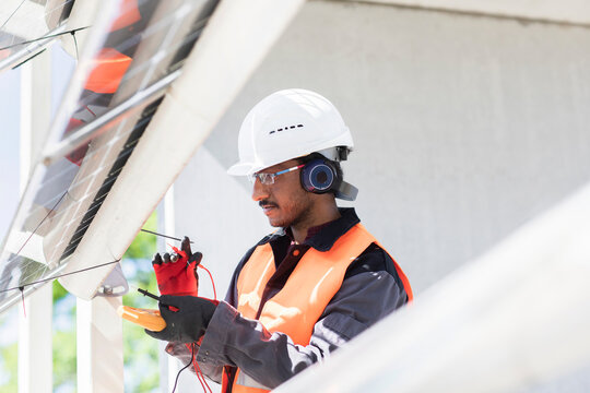 Male engineer wearing hardhat and ear protectors working on construction site.