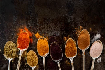 Fototapeten High angle close up of variety of spices on silver spoons. © Image Source