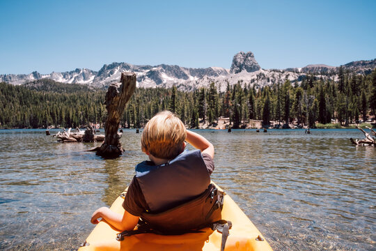 Rear view of boy sitting in kayak on Lake Mary, Mammoth Lakes, California, USA.