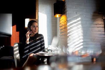 Businesswoman sitting at a table, using mobile phone.
