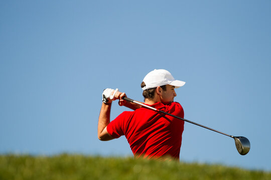 Male golfer teeing off.