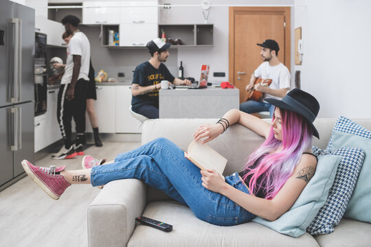 Group Of Friends In Open Plan Apartment, Cooking And Reading.