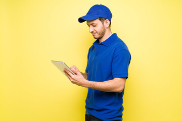 Latin delivery man with a cap using a tablet