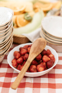 High angle close up of wooden spoon on bowl of strawberries.