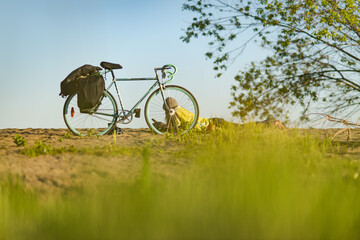 Woman lying on ground next to a bicycle, taking a break during a cycle tour through Canada.