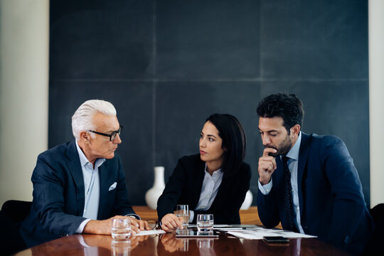Businessmen and woman having discussion at boardroom table