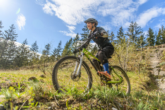 Woman mountain-biking in a forest in the Canadian mountains in British Columbia.