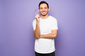 Happy man showing a credit card in a bright background