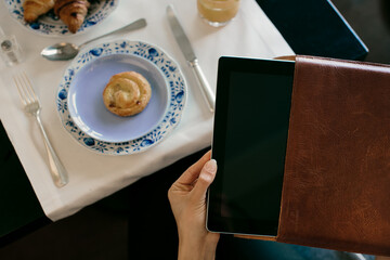 Womans hand removing digital tablet from case whilst having  breakfast at  boutique hotel in Italy
