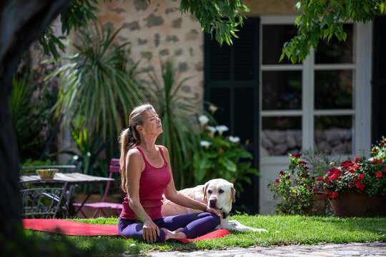 Woman practicing yoga outdoors on lawn in garden.