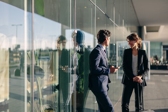 Businessman and businesswoman talking outside glass building, Malpensa, Milan