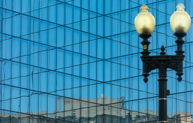 Fototapeta premium Washington, DC, USA - 05 April 2020: Modern blue Glass Facade of an Office Building, ancient Street Lamp blurred in Foreground