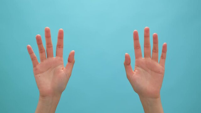 Close up of woman hand showing waving bye on the blue background.