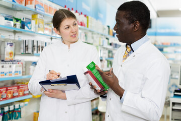 Fototapeta na wymiar male and female pharmacists working at drugstore, checking medicines inventory.