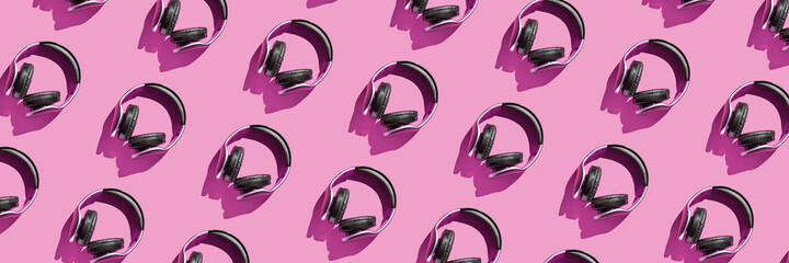 Many same headphones on pink bright background. Modern music concept. Top view repeat layout....