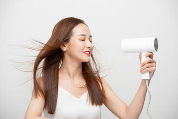 Beautiful Asian girl drying her hair with hairdryer.