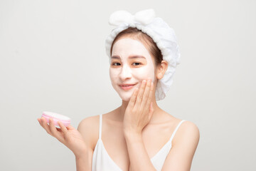 Beauty procedures skincare concept. Young woman applying facial  mud clay mask to her face in bathroom