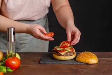 Close-up on the preparation of a magnificent burger.  Gastronomy, recipes, menus, fast food. Juicy hamburger