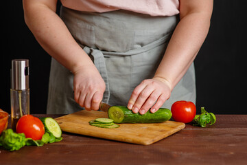 The chef cuts fresh vegetables on a wooden board. Cooking a burger.