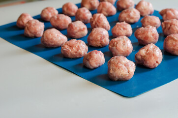 Raw shaped meatballs on blue.