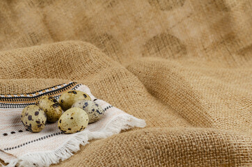 Quail eggs and ethnic napkin on sacking.