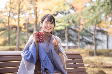 秋の公園でブドウを持つ女性
