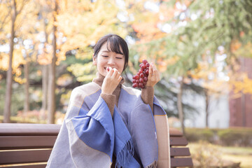 Fototapeta premium 秋の公園でブドウを持つ女性 