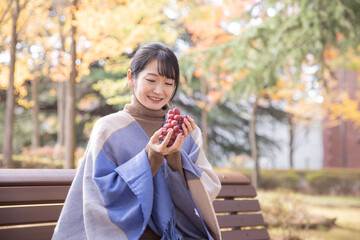 秋の公園でブドウを持つ女性
