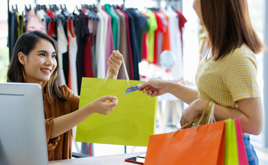 Asian saleswoman and customer with credit card in shop