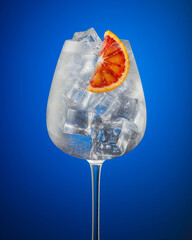 Glass of tasty cold ice lemonade, cocktail with citrus slice isolated on color background